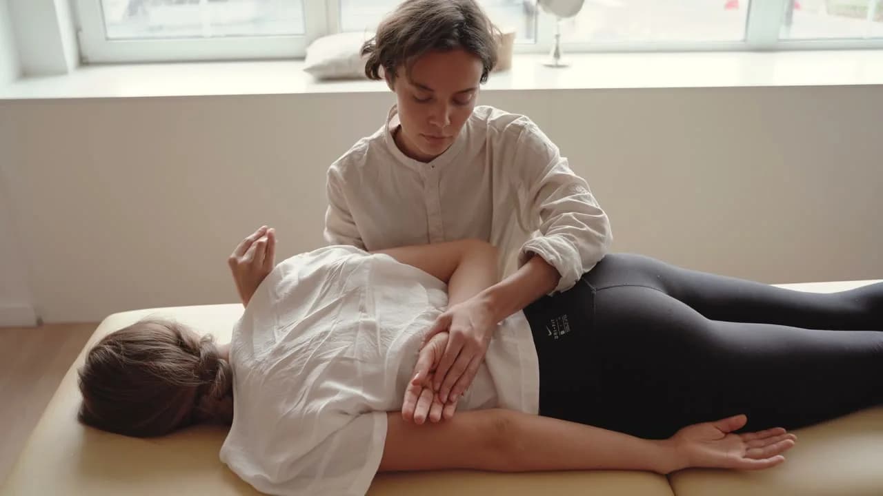 Physiotherapist performing hands-on back therapy during a home visit