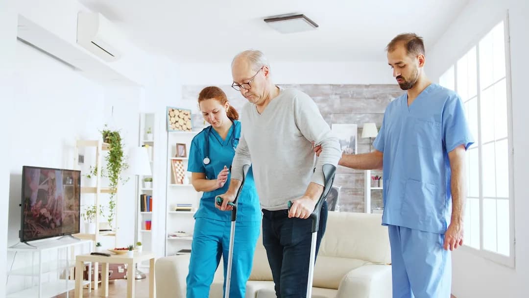 Physiotherapist helping stroke patient with home exercises in Pune living room